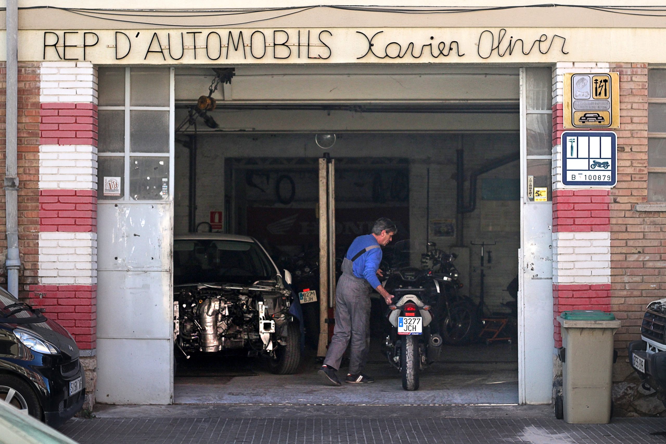 Xevi Oliver entrant una moto al seu taller de reparació